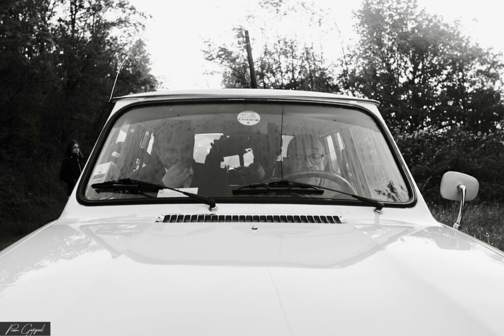 Voiture vue de face sur une route bordée d’arbres