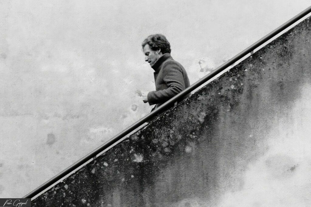 Homme descendant un escalier extérieur en noir et blanc